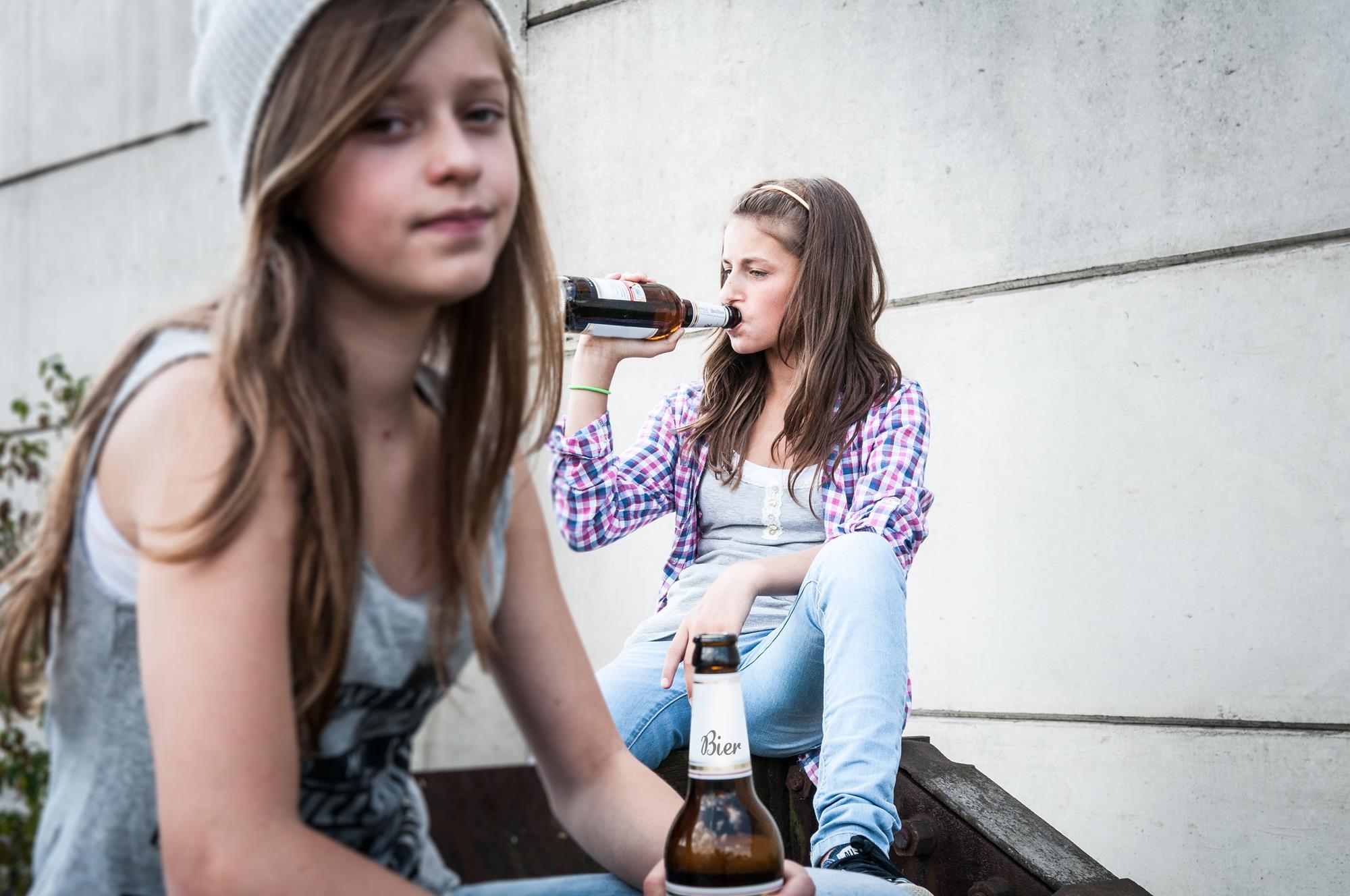Dwie nastolatki piją alkohol na schodach.